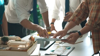Close up of smart business team hand working together to plan design while looking at project plan from tablet and discussing about blueprint and building construction at meeting table. Alimentation.
