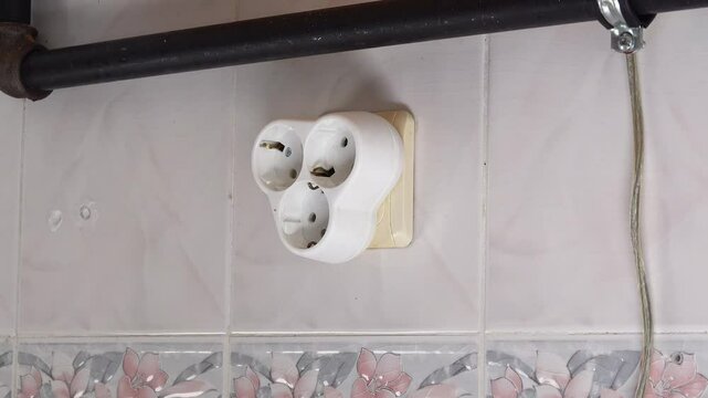 Close up view of plugging a triple outlet into a socket.
