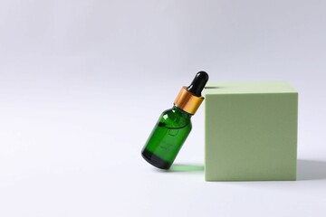 Skin care with cosmetic facial serum. Glass bottle with a pipette on a white  background. Dry skin care product. Essential oil for moisturizing the skin of the body. Brand layout.
