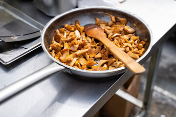 A spacious pan filled with an assortment of mushrooms and a sturdy spoon is perfect for stirring gourmet recipes or everyday meals, essential for every chef and home cook