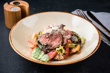 Fresh meat salad with beef slices, tomatoes, parmesan cheese, pickled cucumber, lettuce and sauce.