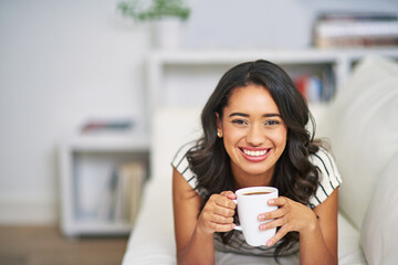 Portrait, woman and happy on sofa with coffee, relax and comfort on weekend at home. Female person, smile and warm beverage on couch for peace, wellness and morning in Brazil apartment for rest