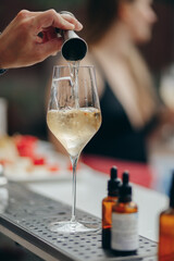 Bartender pouring red wine into a glass with ice cube