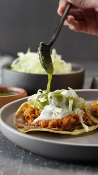 Mexican woman pours green sauce on toast, vertical mexican food