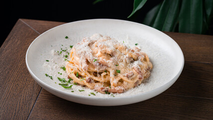 Lunch pasta with bacon, parmesan cheese, cream sauce and greens.