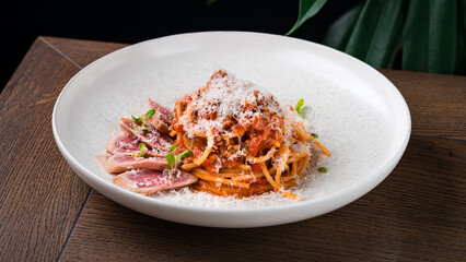 Lunch pasta with bolognese sauce, parmesan cheese, tomatoes, tuna and herbs.