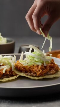 Vertical mexican food, placing chopped lettuce on mexican toasts