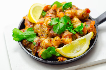 A black pan with shrimp and lemon slices