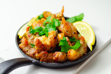 A black pan with shrimp and lemon slices