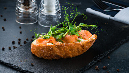 Bruschetta with salmon slices, cream cheese, arugula and green peas.