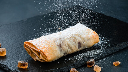 Piece of cherry strudel with powdered sugar.