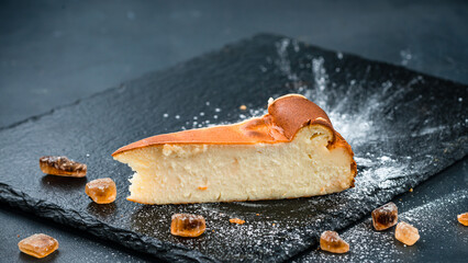 Piece of vanilla cheesecake with sweets and powdered sugar.