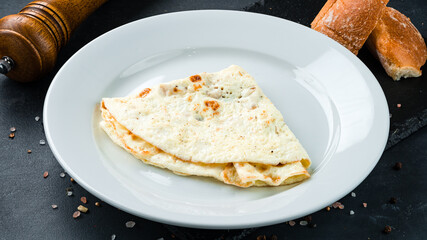 Egg omelet with bread, salt and pepper on a dark background.