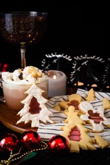 Festive holiday table setting with hot chocolate and decorated Christmas cookies, with warm candlelight and seasonal decorations.
