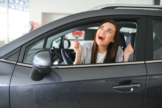 Young woman sitting in car holding keys