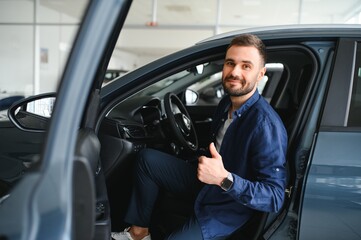 Young man is choosing a new vehicle in car dealership