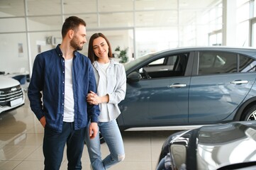 The successful visit to the dealership. Happy young couple chooses and buying a new car for the family