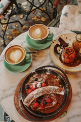 Breakfast food with coffee in cups and tasty desserts on a cozy cafe table in autumn