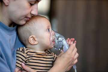 Mom giving nebulizer breathing treatment to sick infant baby at home