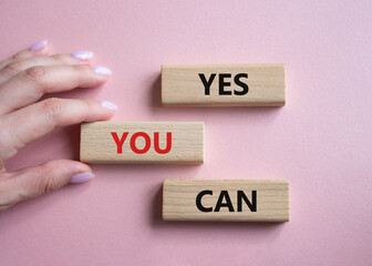 Yes You Can symbol. Concept word Yes You Can on wooden blocks. Beautiful pink background. Businessman hand. Business and Yes You Can concept. Copy space.