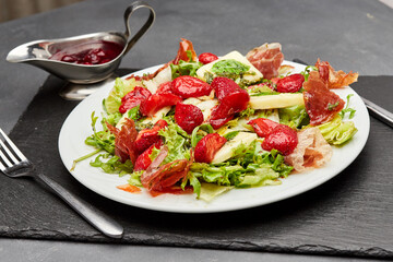 Salad with fresh strawberries, prosciutto, and mixed greens, topped with a light vinaigrette