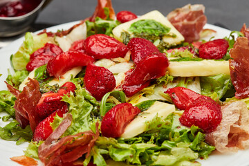 Salad with fresh strawberries, prosciutto, and mixed greens, topped with a light vinaigrette