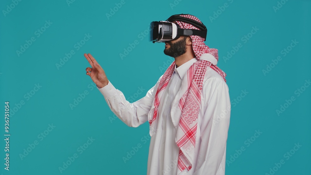 Poster middle eastern guy using vr glasses in studio, enjoying shoot with virtual reality simulation on int