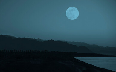 Fototapeta premium dusk on Black sea coast . Caucasian mountain. Batumi, Adjara, Georgia. beautiful sundown over rock. empty seacoast. no people. after sunset. full moon above peak. night scene. midnight. blue heaven.