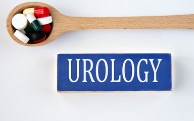 UROLOGY - word on a wooden blue block on a white background with a spoon with pills in the background