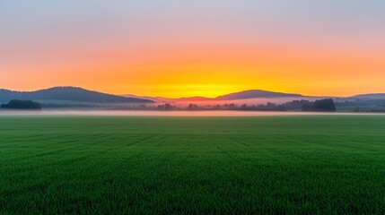 Breathtaking sunrise over green fields and distant hills, creating a serene landscape filled with soft colors and tranquility.
