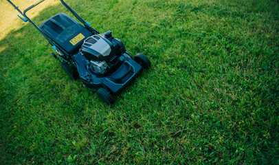 A lawn mower sits on a freshly cut lawn, ready for use in a well-maintained garden. Essence of outdoor maintenance, showcasing the tools essential for keeping a lawn in perfect condition.