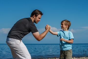 Happy father and son have fun and wrestling on lake shore