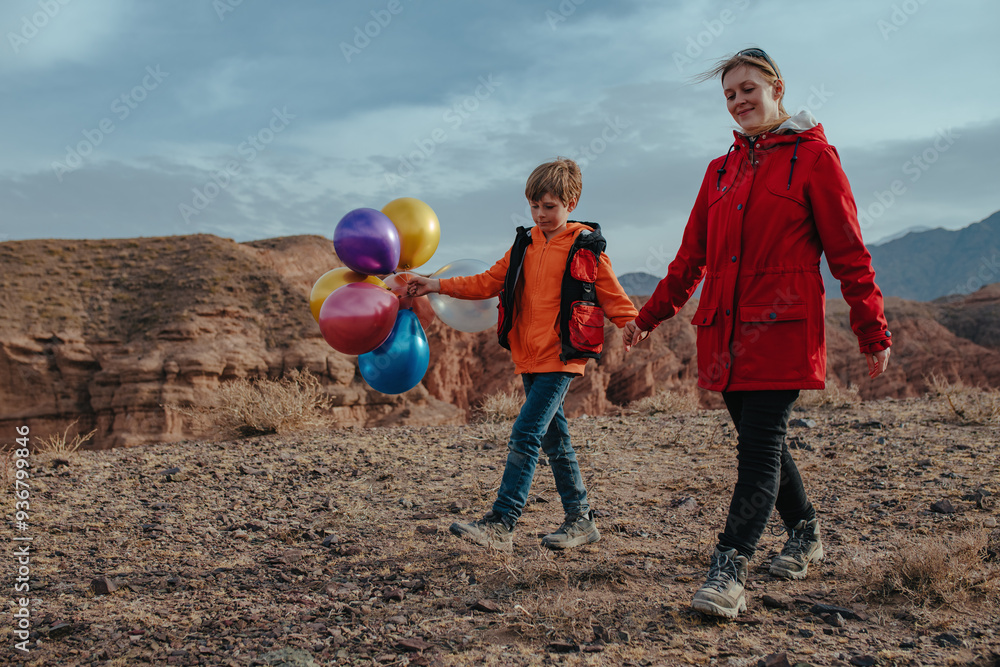 Poster Boy hiker with balloons and his mother walking in the mountains