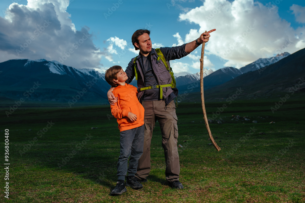 Canvas Prints Man hiker with his son standing in the mountains at dusk, father pointing in the distance