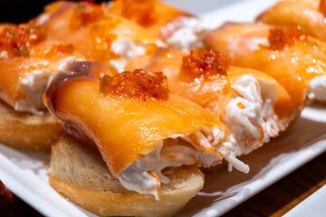 Typical snacks of Basque Country, pinchos or pinxtos skewers with small pieces of bread, fish, sea food, sweet green pepper served in bar in San-Sebastian or Bilbao, Spain