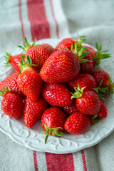 Plate with french organic red ripe sweet strawberries Fraises de Plougastel, harvested in France