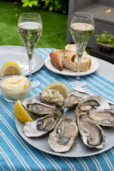 Champagne sparkling wine in glasses and oysters from Arcachon bay served on oysters farm in Gujan-Mestras, with lemon, baquette bread, butter