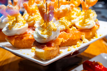 Typical snacks of Basque Country, pinchos or pinxtos skewers with small pieces of bread, fish, sea food, sweet green pepper served in bar in San-Sebastian or Bilbao, Spain