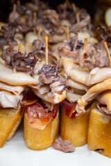 Typical snacks of Basque Country, pinchos or pinxtos skewers with small pieces of bread, fish, sea food, sweet green pepper served in bar in San-Sebastian or Bilbao, Spain