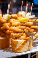 Typical snacks of Basque Country, pinchos or pinxtos skewers with small pieces of bread, fish, sea food, sweet green pepper served in bar in San-Sebastian or Bilbao, Spain