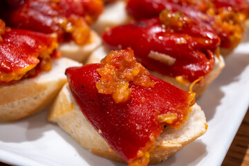 Typical snacks of Basque Country, pinchos or pinxtos skewers with small pieces of bread, fish, sea food, sweet green pepper served in bar in San-Sebastian or Bilbao, Spain