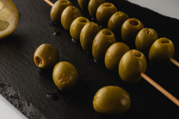green olives on a skewer on a black board