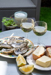 Plate with fresh live oysters with citron, bread, butter and white wine served at restaurant in oyster-farming village, Arcachon bay, Gujan-Mestras port, France