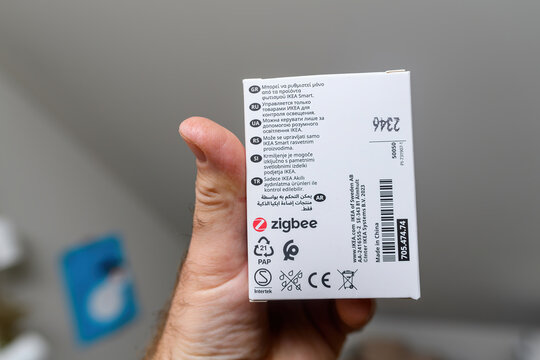 Paris, France - May 21, 2024: A male hand holds a Zigbee IKEA Wi-Fi controlled smart lamp, preparing to replace a traditional lamp, highlighting the transition to smart home technology