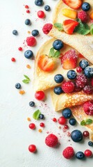 A close-up shot of a plate of pancakes topped with fresh berries, powdered sugar and mint leaves.