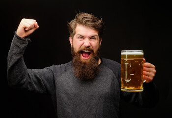 Happy bearded man with beer mug celebrating victory with raised hand. Excited man drinking draft delicious beer. Winner expression. Handsome male with mug beer making winning gesture with raised arm.