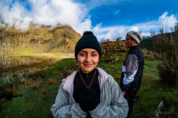Portrait of a Smiling Latina Woman in Black Hat and Beige Jacket Against Green Hills Background