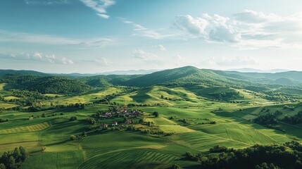 Obraz premium Aerial View of Lush Green Rolling Hills and Small Village in a Valley.