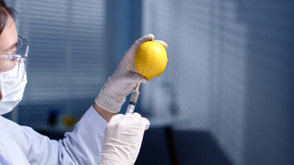 frontal angle, a scientist uses a needle to extract the essence from a lemon in the center of the...