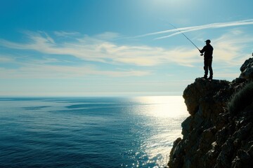 Silhouette of a fisherman holding a fishing rod standing on a cliff by the sea